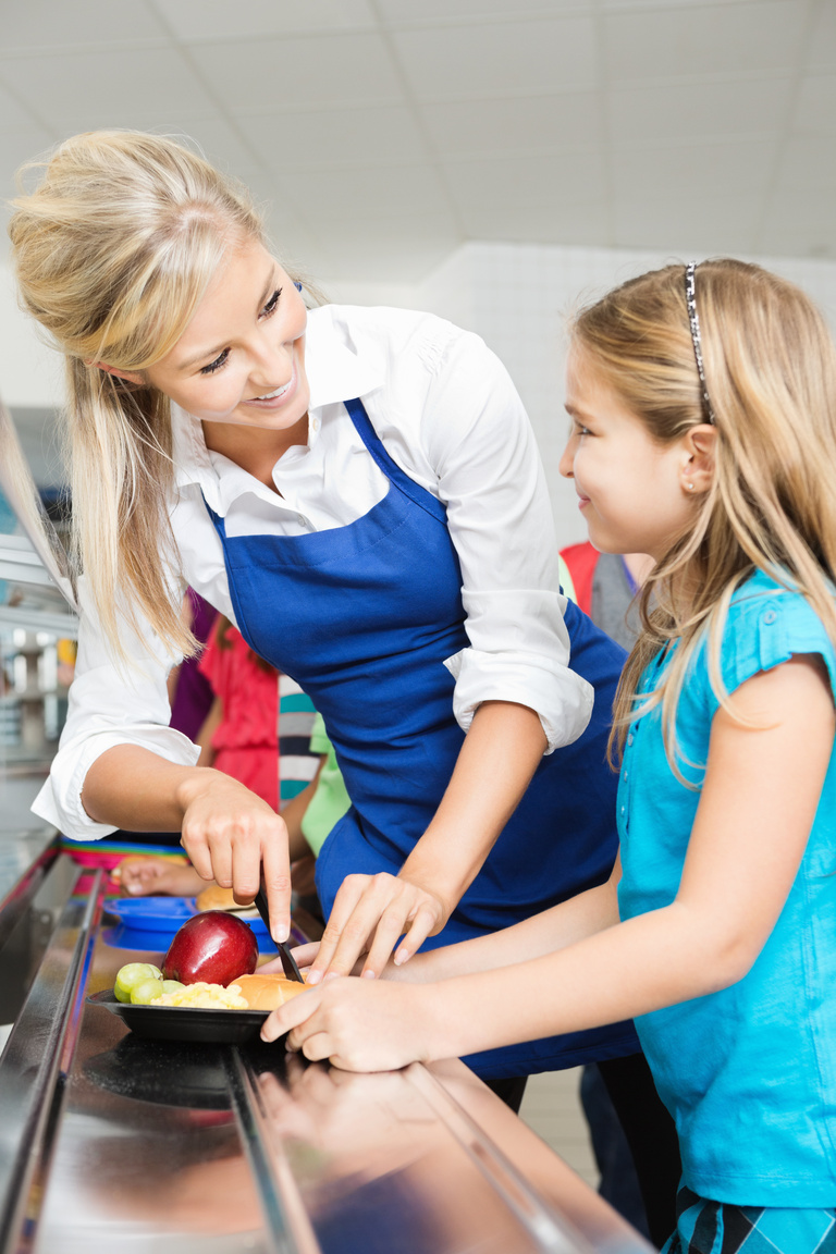 Friendly cafeteria worker assisting student buying lunch at school